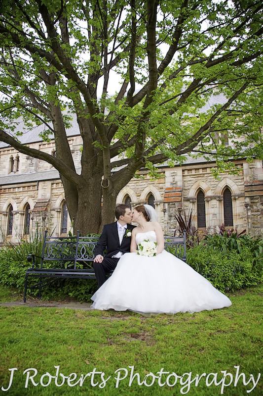 Couple kissing under tree in church gardens St Thomas' North Sydney - wedding photography sydney